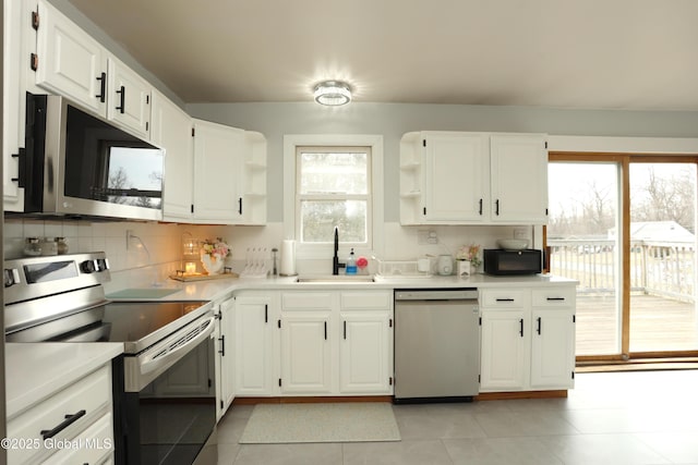 kitchen with open shelves, a sink, appliances with stainless steel finishes, white cabinetry, and backsplash