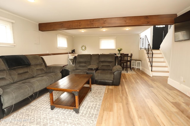 living room featuring beamed ceiling, ornamental molding, stairway, light wood-style floors, and baseboards