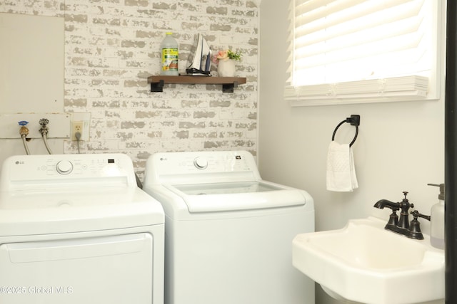 washroom with a sink, brick wall, and washer and dryer