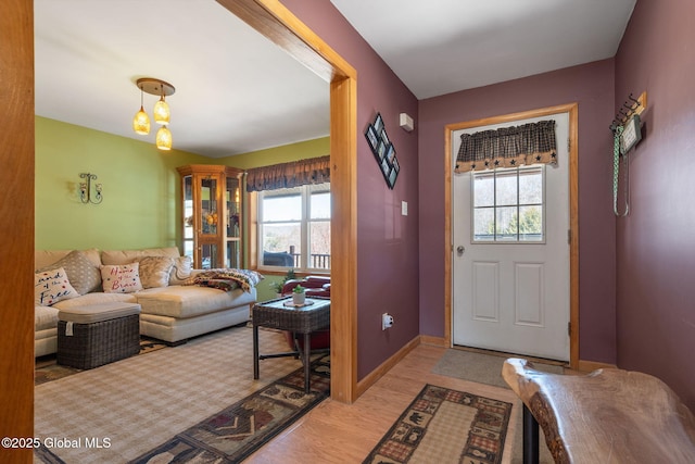 foyer entrance featuring a wealth of natural light, baseboards, and light wood finished floors