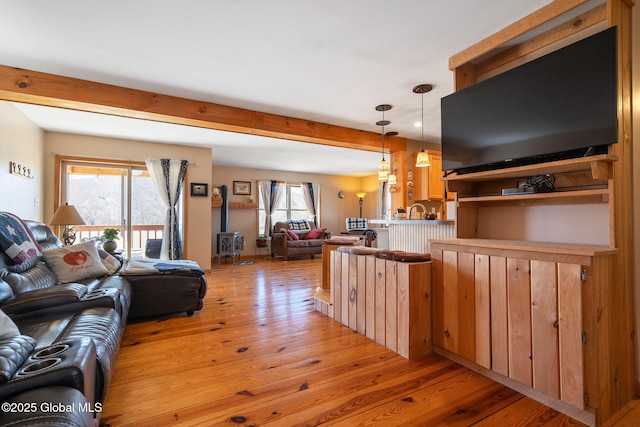 living room with a wealth of natural light, beamed ceiling, and light wood finished floors