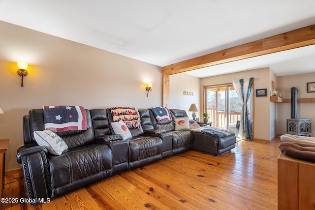 living room with beam ceiling, light wood-style flooring, and a wood stove