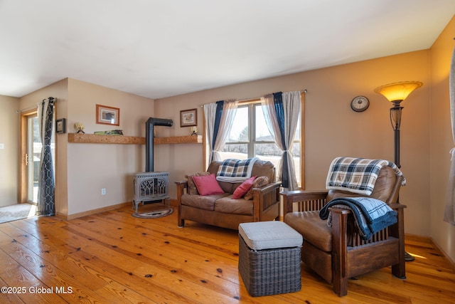 living room with baseboards, a wood stove, and light wood-style floors