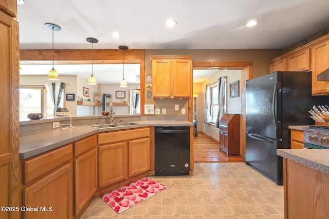 kitchen with a sink, black appliances, recessed lighting, and hanging light fixtures