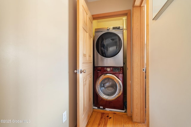 washroom featuring laundry area, stacked washer / drying machine, and wood finished floors