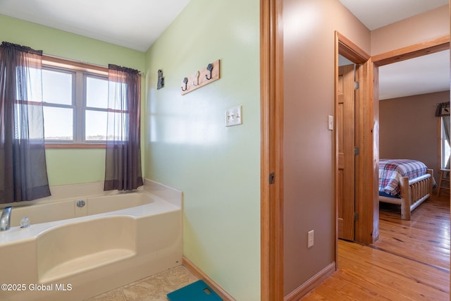 full bathroom featuring a garden tub, wood finished floors, and baseboards