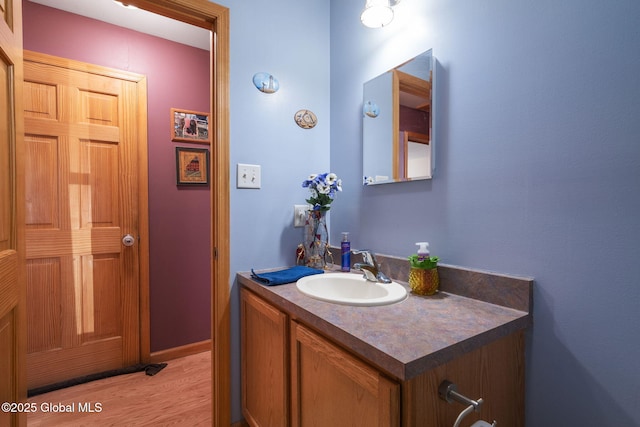 bathroom with baseboards, wood finished floors, and vanity