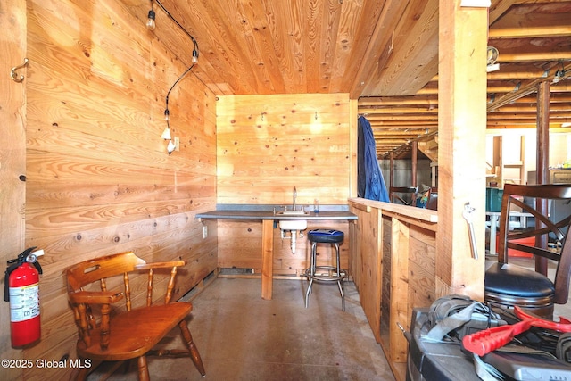 misc room featuring wooden walls, wood ceiling, and finished concrete flooring