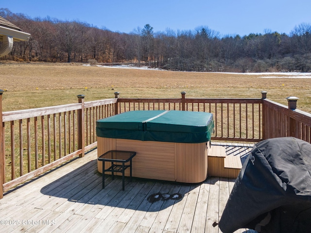 deck featuring area for grilling, a view of trees, and a hot tub