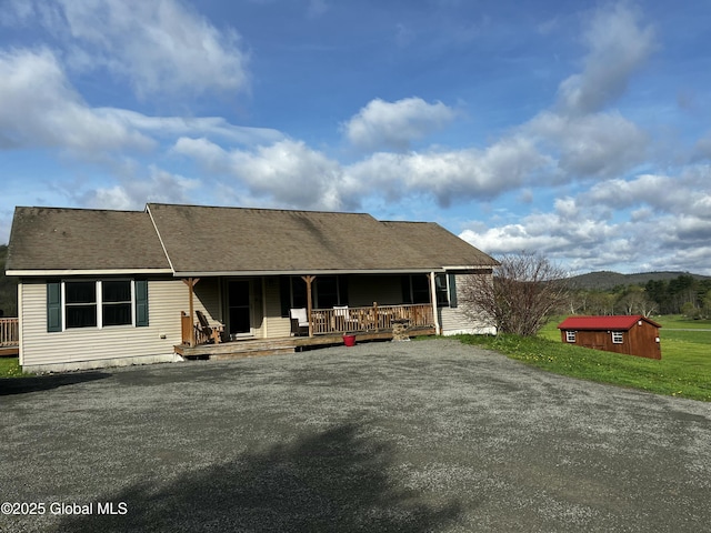 back of house featuring covered porch, an outdoor structure, and a storage unit