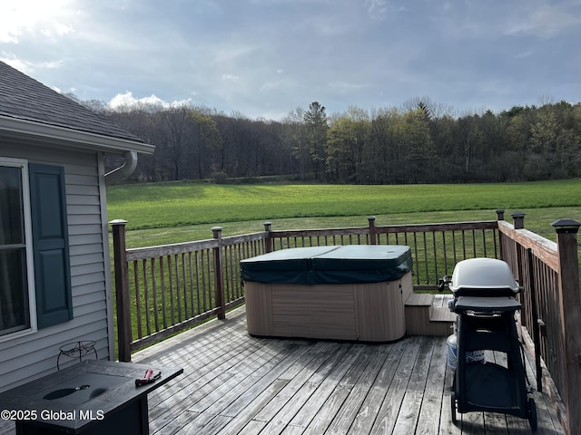 wooden deck with a hot tub, a forest view, a yard, and area for grilling