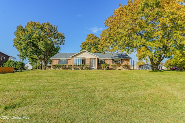 single story home featuring brick siding, a front yard, and a shingled roof