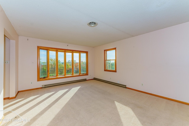 empty room with visible vents, a baseboard heating unit, baseboards, light carpet, and baseboard heating