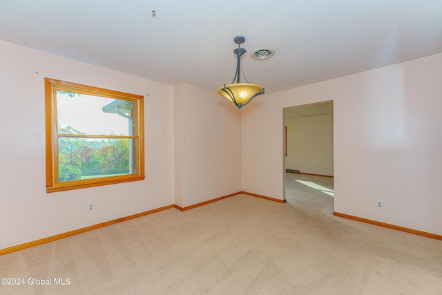 empty room featuring visible vents, light colored carpet, a textured ceiling, and baseboards