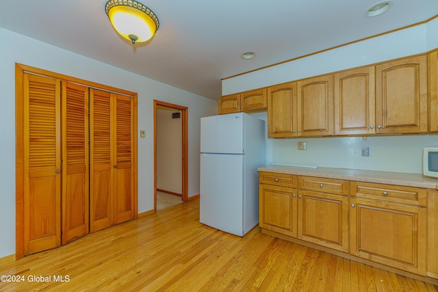 kitchen featuring white appliances, brown cabinetry, baseboards, light wood finished floors, and light countertops