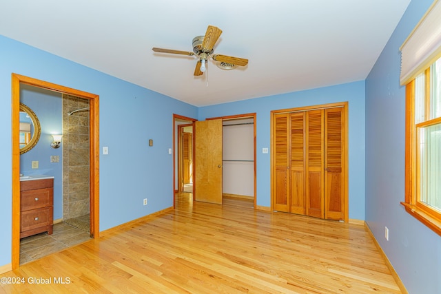 unfurnished bedroom featuring baseboards, two closets, and light wood-style flooring