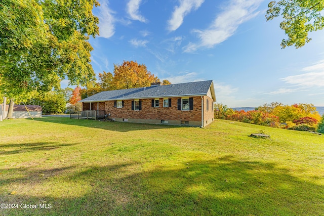 exterior space with brick siding, a lawn, and a chimney