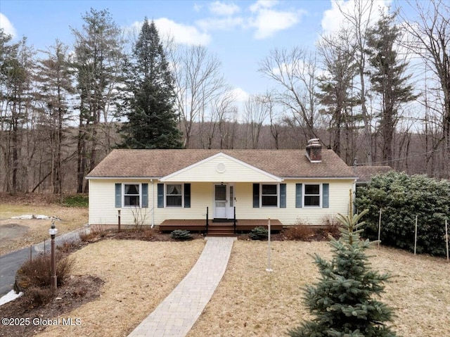 view of front of property featuring covered porch, roof with shingles, and a chimney