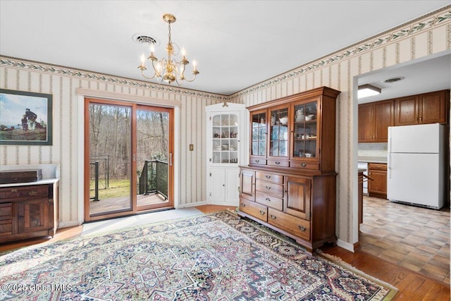 dining area with a chandelier, light wood finished floors, and wallpapered walls