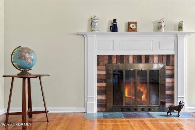 interior details with wood finished floors, a fireplace, and baseboards