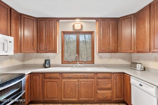 kitchen featuring backsplash, brown cabinets, white appliances, and a sink