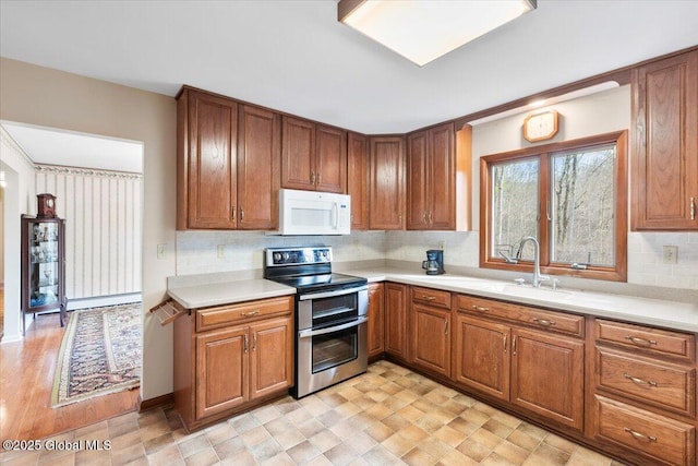 kitchen featuring white microwave, light countertops, range with two ovens, brown cabinetry, and a sink