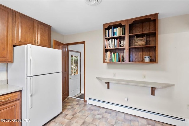 kitchen with a baseboard radiator, open shelves, freestanding refrigerator, light countertops, and brown cabinets