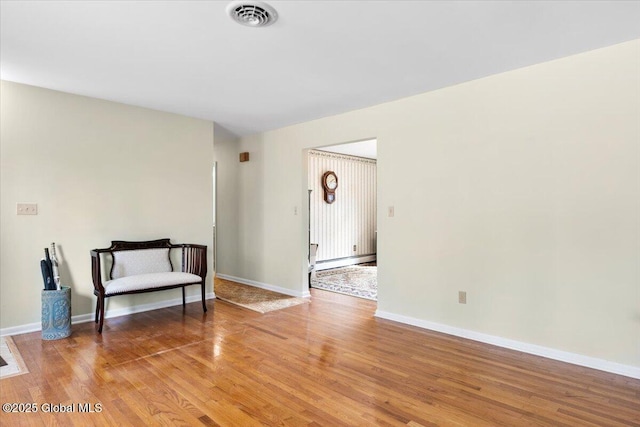 unfurnished room with light wood-type flooring, a baseboard radiator, baseboards, and visible vents