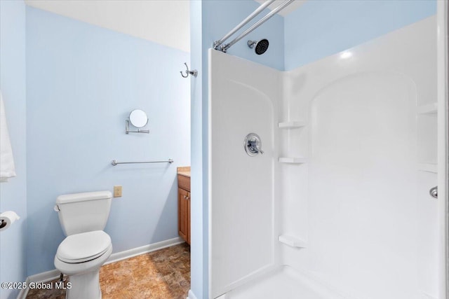 bathroom with baseboards, toilet, walk in shower, and vanity