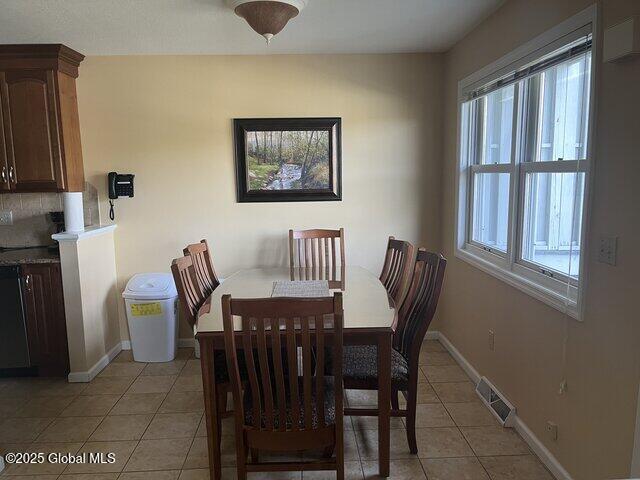 dining area featuring light tile patterned floors, visible vents, plenty of natural light, and baseboards