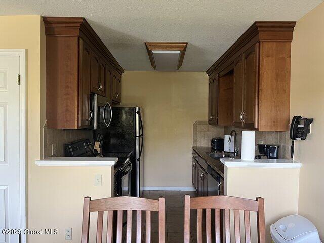 kitchen featuring dark tile patterned flooring, a sink, decorative backsplash, stainless steel microwave, and range