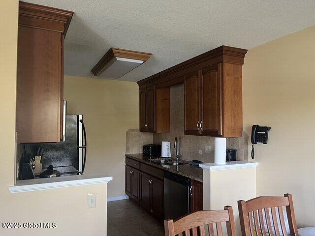 kitchen with tile patterned floors, a sink, tasteful backsplash, a textured ceiling, and dishwasher