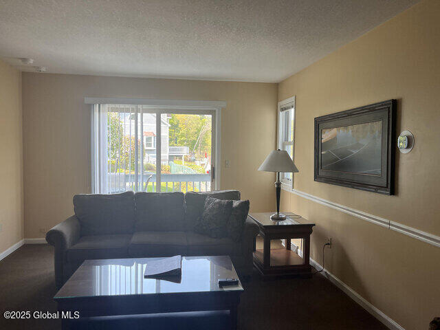 living area with a textured ceiling, baseboards, and dark colored carpet