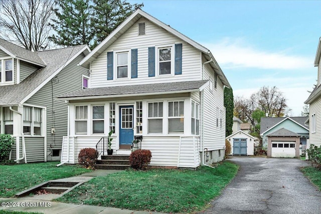 view of front of property with a detached garage, a front lawn, entry steps, an outbuilding, and driveway