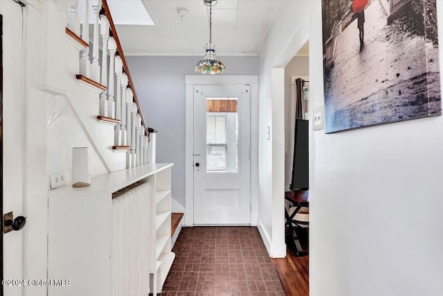 entrance foyer featuring baseboards, stairs, brick floor, and ornamental molding