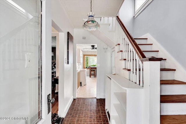 interior space featuring brick floor, stairway, and a ceiling fan