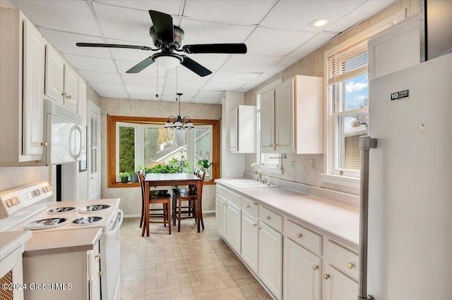 kitchen with white appliances, light countertops, a paneled ceiling, and a sink