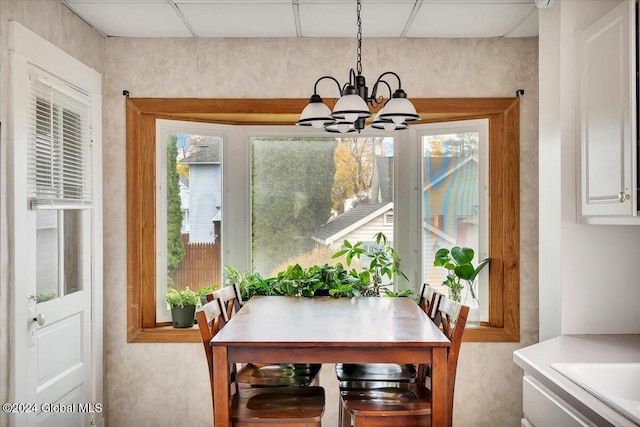 dining space featuring a notable chandelier and a drop ceiling