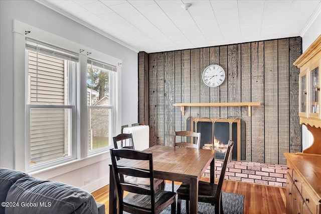 dining area with ornamental molding, a fireplace, and wood finished floors