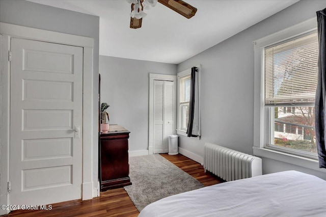 bedroom with dark wood finished floors, radiator heating unit, baseboards, and a closet