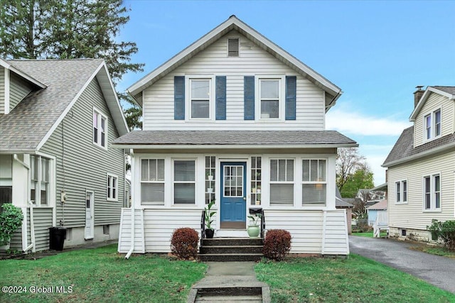 view of front facade featuring entry steps, a front yard, and roof with shingles