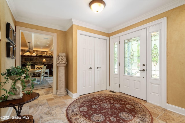 foyer entrance featuring stone tile flooring, baseboards, and ornamental molding