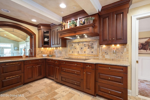 kitchen with light stone counters, ornamental molding, decorative backsplash, a sink, and black electric cooktop