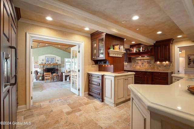 kitchen with stone tile floors, a fireplace, recessed lighting, light countertops, and crown molding