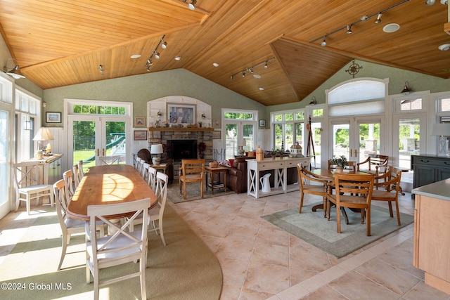 dining room with track lighting, french doors, wooden ceiling, a fireplace, and vaulted ceiling