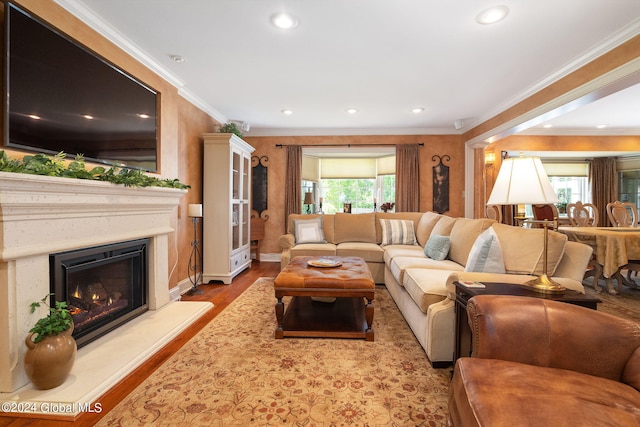 living room with wood finished floors, baseboards, recessed lighting, ornamental molding, and a glass covered fireplace