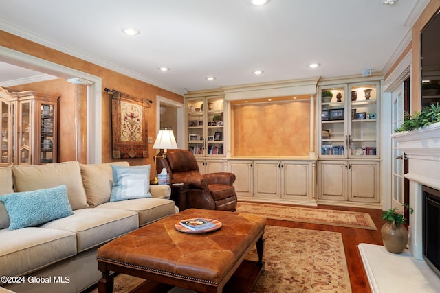 living room with a fireplace with raised hearth, recessed lighting, crown molding, and light wood-style floors