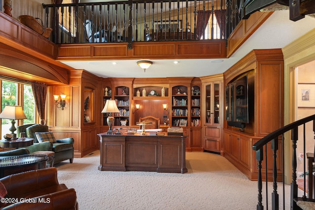 office space featuring light carpet, wood walls, and a high ceiling