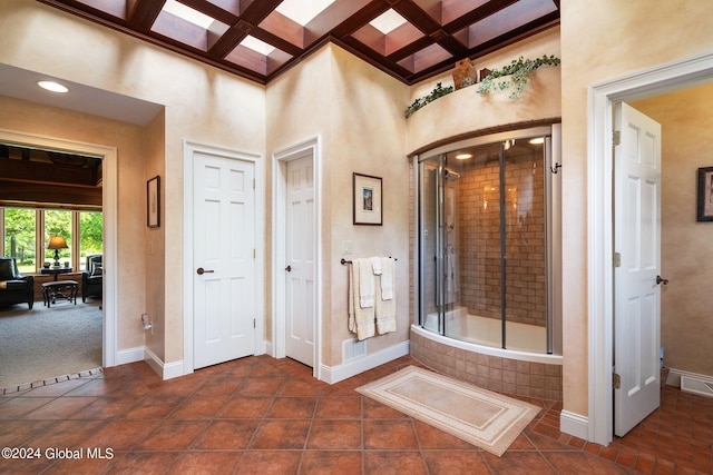 bathroom with baseboards, coffered ceiling, tiled shower, a tub, and beamed ceiling