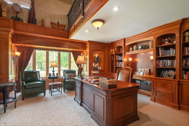 office area with built in desk, light colored carpet, a textured ceiling, and a high ceiling